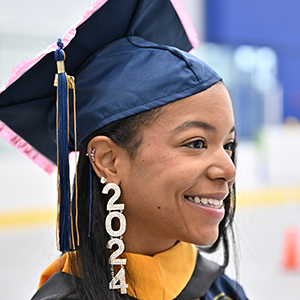 Profile view of a graduate with 2024 earrings.