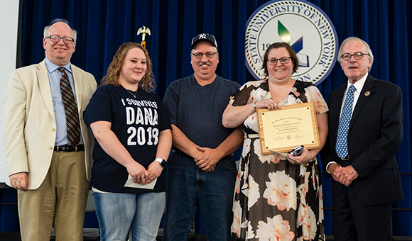 Food services representatives stand on stage with the College Council chair and college president.