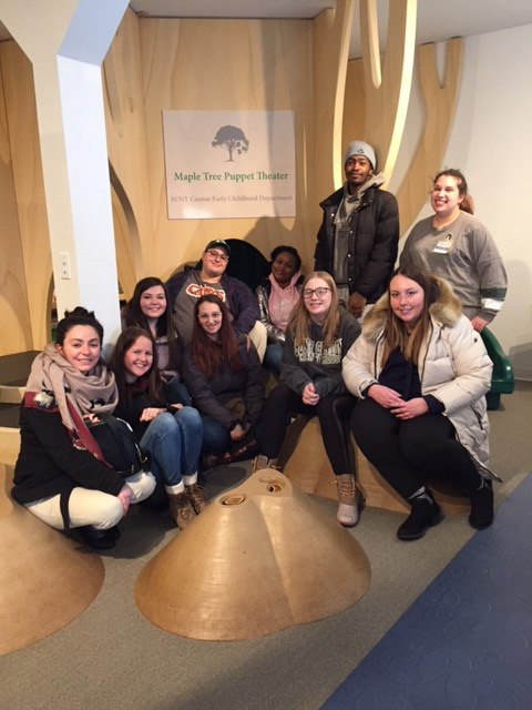 Early Childhood students gather around the maple tree at the North Country Children's Museum.