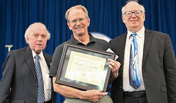 Chairman Ronald O'Neil and President Zvi Szafran present Dr. Ken Erickson with the President's Meritorious Service Award.
