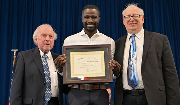 Nicodeme Auguste receives the President's Meritorious Award from Chairman Ronald O'Neil and President Zvi Szafran.