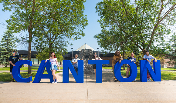 Students pose with giant Canton letters in front of the Miller Campus Center.