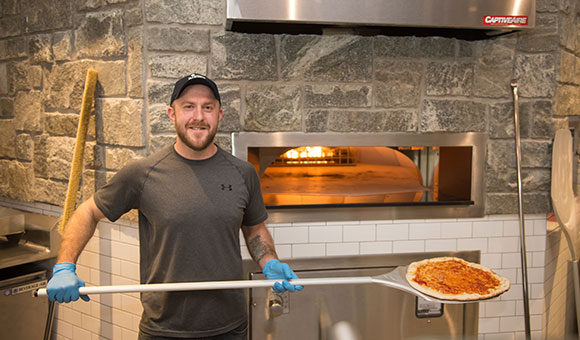A server takes a fresh pizza from the oven