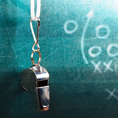 Whistle hangs in front of X's and O'x on a chalkboard.