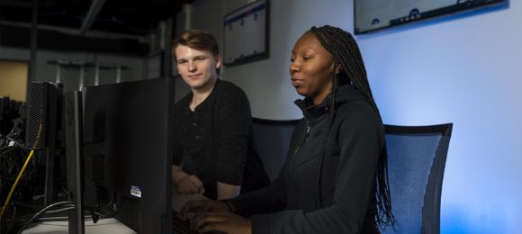 Two students work on a computer in the Cybersecurity lab.