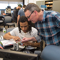 Dave Hartley works with a student on an electrical connection.