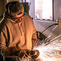 Sparks fly while a student uses a grinder.
