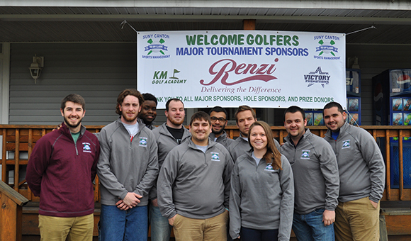 Students pose in front of Tournament banner.