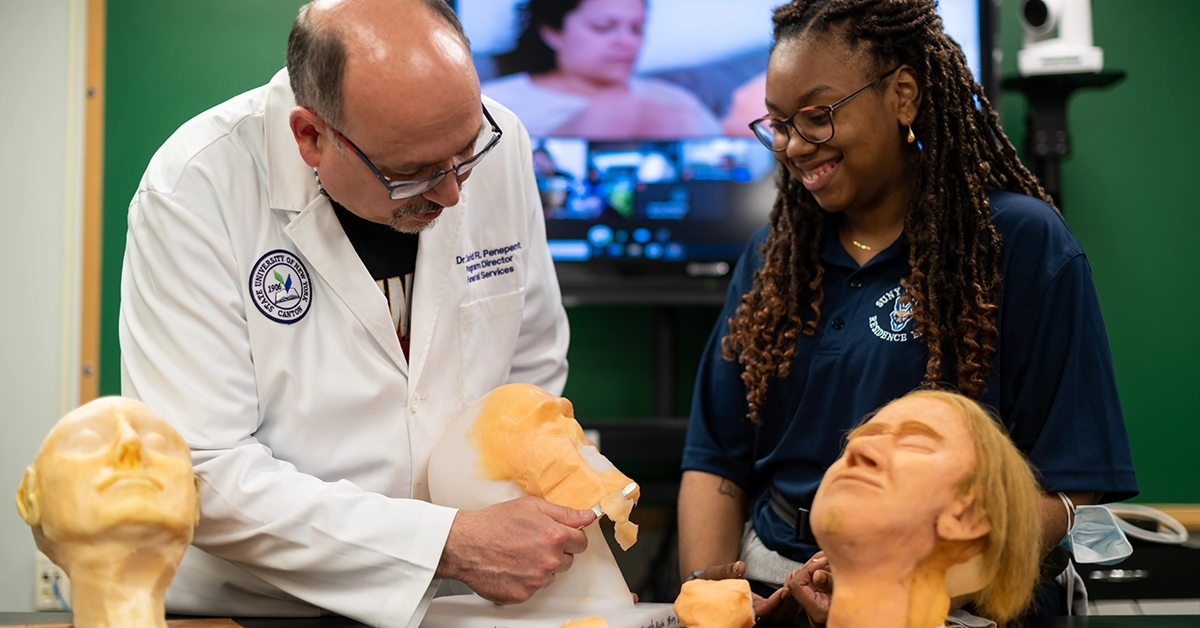 Professor Penepent assists a student with a death mask in the Funeral Services reconstruction lab.