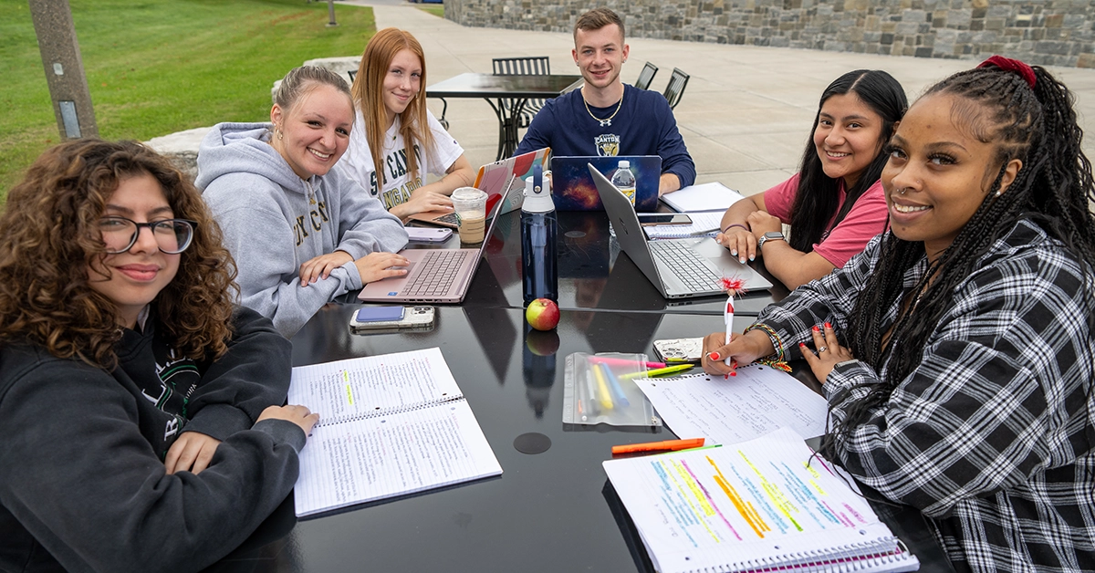 A group of students study at a table outside Dana Hall.