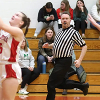 Kyle Fennell runs down the sideline while officiating a girls basketball game.