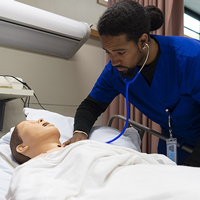 A nursing student checks the pulse and heart rate of a dummy patient.