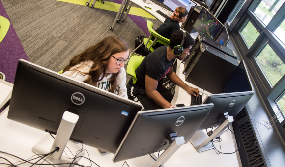 Three students working on computers in class