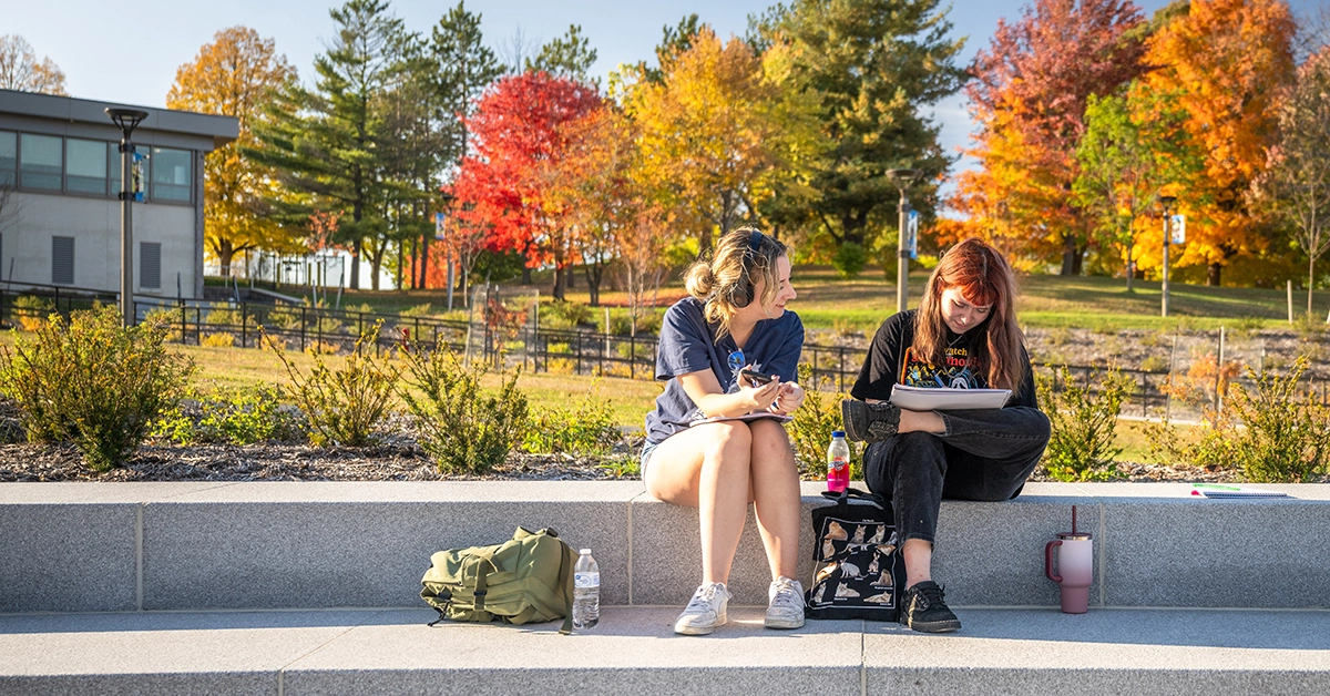 Two students study on a beautiful fall day in the Roselle Academic Plaza.