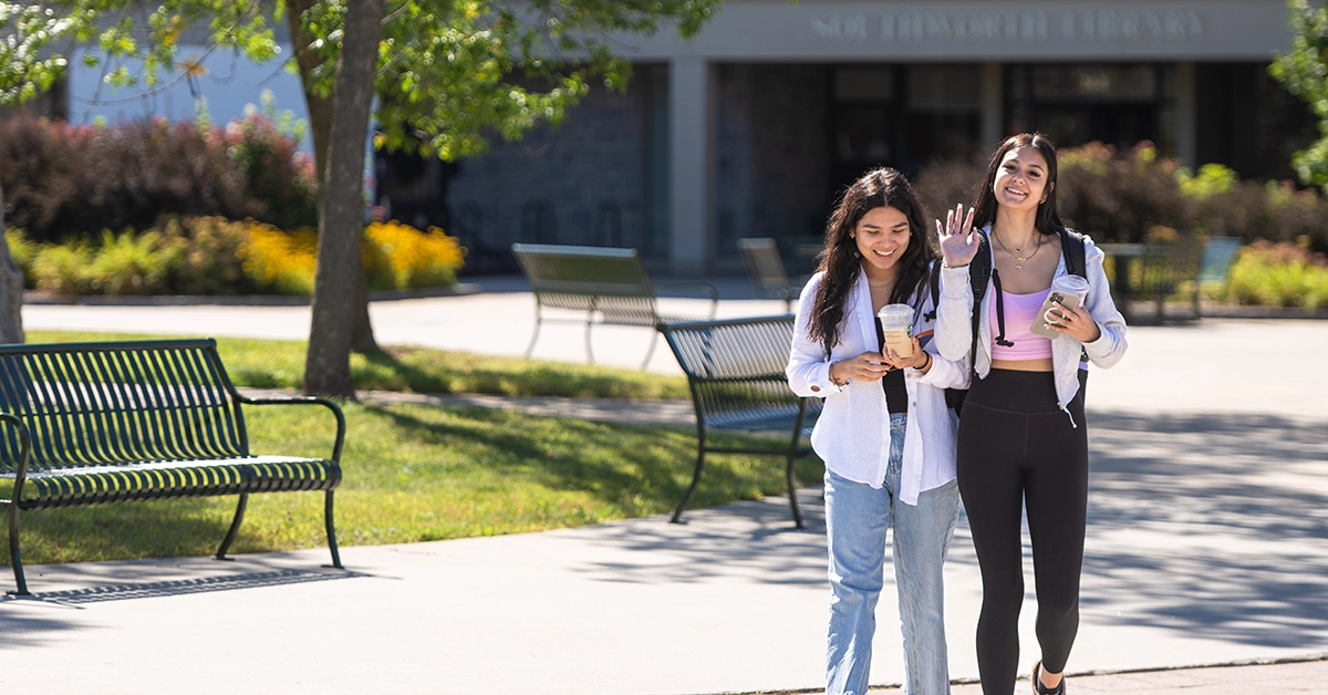 Two students walk through the Roselle Academic Plaza. One waves to the camera.